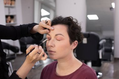 Profesyonel makyöz güzellik salonundaki güzel kadın mankene makyaj yapıyor..                      