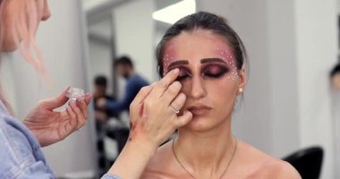 Makyöz, güzellik salonundaki genç bayana göz farı uyguluyor..             