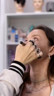 Profesyonel makyöz güzellik salonundaki güzel bayan müşteriye makyaj yapıyor.         