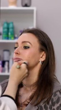 Profesyonel makyöz. Güzellik salonunda genç bir kadının yüzüne makyaj yapıyor..                       