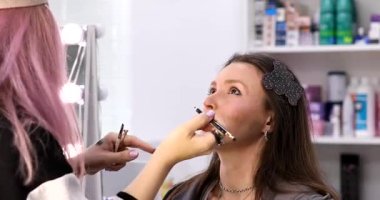Kadın makyaj sanatçısı güzellik salonundaki kadın müşterisine makyaj yapıyor.        