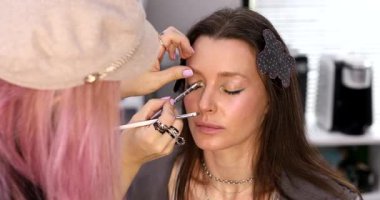 Kadın makyaj sanatçısı güzellik salonundaki kadın müşterisine makyaj yapıyor.        