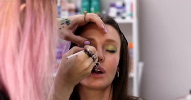 Makyaj sanatçısı güzellik salonunda çalışıyor. Profesyonel makyaj ustası tarafından uygulanan kadın portresi.          