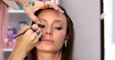 Kadın makyaj sanatçısı güzellik salonundaki kadın müşterisine makyaj yapıyor.        