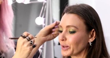 Kadın makyaj sanatçısı güzellik salonundaki kadın müşterisine makyaj yapıyor.        