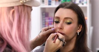 Kadın makyaj sanatçısı güzellik salonundaki kadın müşterisine makyaj yapıyor.        