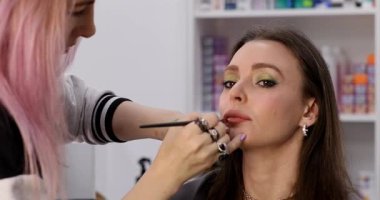 Kadın makyaj sanatçısı güzellik salonundaki kadın müşterisine makyaj yapıyor.        