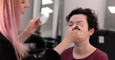 Profesyonel makyöz güzellik salonundaki güzel kadın mankene makyaj yapıyor..                      