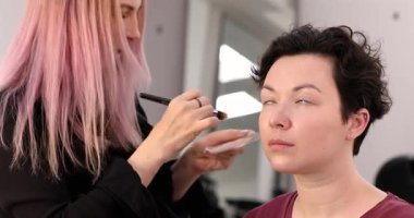 Profesyonel makyöz güzellik salonundaki güzel kadın mankene makyaj yapıyor..                      