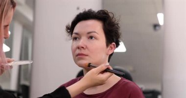 Profesyonel makyöz güzellik salonundaki güzel kadın mankene makyaj yapıyor..                      