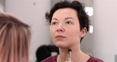 Profesyonel makyöz güzellik salonundaki güzel kadın mankene makyaj yapıyor..                      