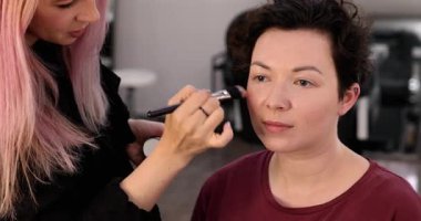 Profesyonel makyöz güzellik salonundaki güzel kadın mankene makyaj yapıyor..                      