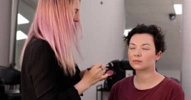 Profesyonel makyöz güzellik salonundaki güzel kadın mankene makyaj yapıyor..                      