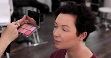 Profesyonel makyöz güzellik salonundaki güzel kadın mankene makyaj yapıyor..                      