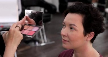 Profesyonel makyöz güzellik salonundaki güzel kadın mankene makyaj yapıyor..                      