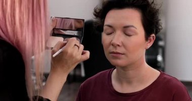 Profesyonel makyöz güzellik salonundaki güzel kadın mankene makyaj yapıyor..                      