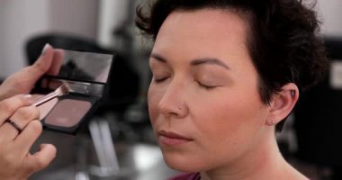 Profesyonel makyöz güzellik salonundaki güzel kadın mankene makyaj yapıyor..                      