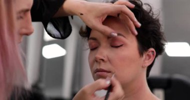 Profesyonel makyöz güzellik salonundaki güzel kadın mankene makyaj yapıyor..                      