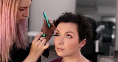 Profesyonel makyöz güzellik salonundaki güzel kadın mankene makyaj yapıyor..                      