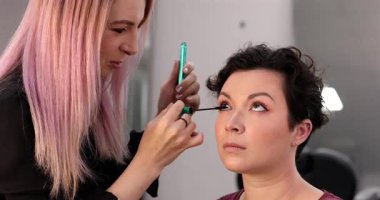 Profesyonel makyöz güzellik salonundaki güzel kadın mankene makyaj yapıyor..                      