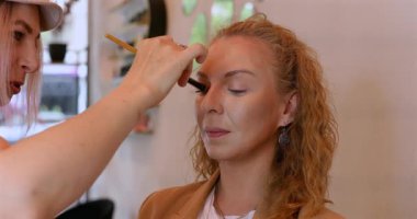 Profesyonel makyöz güzellik salonundaki güzel kadın mankene makyaj yapıyor..                      