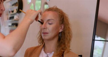 Profesyonel makyöz güzellik salonundaki güzel kadın mankene makyaj yapıyor..                      