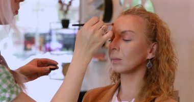 Profesyonel makyöz güzellik salonundaki güzel kadın mankene makyaj yapıyor..                      