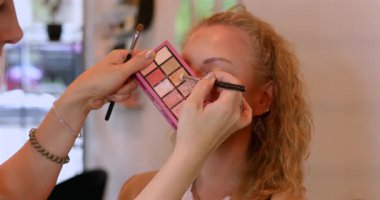 Profesyonel makyöz güzellik salonundaki güzel kadın mankene makyaj yapıyor..                      