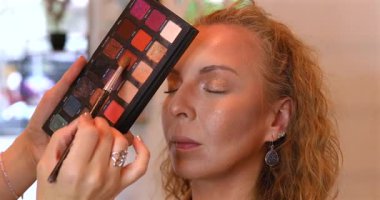 Profesyonel makyöz güzellik salonundaki güzel kadın mankene makyaj yapıyor..                      