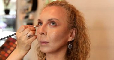 Profesyonel makyöz güzellik salonundaki güzel kadın mankene makyaj yapıyor..                      