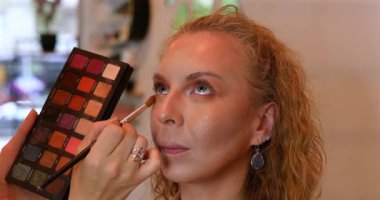 Profesyonel makyöz güzellik salonundaki güzel kadın mankene makyaj yapıyor..                      