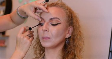 Profesyonel makyöz güzellik salonundaki güzel kadın mankene makyaj yapıyor..                      