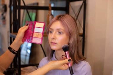 Profesyonel makyöz güzellik salonundaki güzel kıza makyaj yapıyor..                     