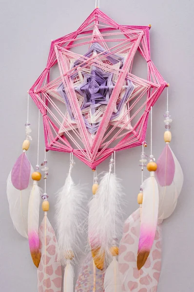 灰色の背景に羽とアメジストの宝石を持つ手作りの密教織りマンダラ魔法の夢のキャッチャー ヨガルームインテリアのための瞑想ツール ロイヤリティフリーのストック写真