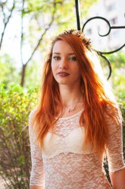 Güzel, kibirli, ince, uzun kızıl saçlı bir kızın yakın plan portresi kameraya soğuk bakıyor.