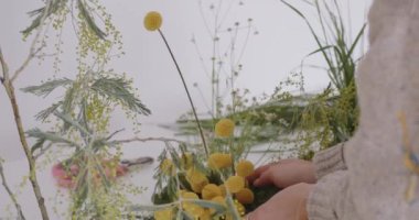 female doing new bouquet. Girl working in flower shop studio. Female florist artist cleans flowers for a beautiful bouquet, workplace view. High quality 4k footage