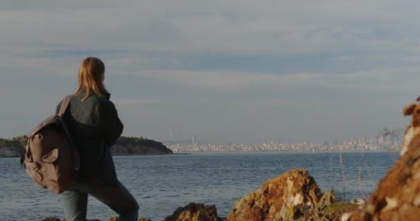 Μια Γυναίκα Στον Γκρεμό Σακίδιο Κοιτάζει Την Πόλη Ταξιδιώτης Στέκεται — Αρχείο Βίντεο
