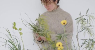 female doing new bouquet. Girl working in flower shop studio. Female florist artist cleans flowers for a beautiful bouquet, workplace view. High quality 4k footage