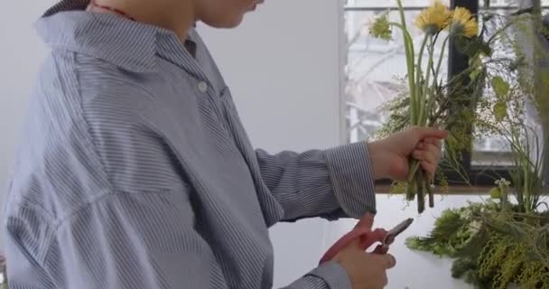 女人在做新的花束 在花店工作室工作的女孩女花匠为了漂亮的花束和工作场所的景观而清洁花朵 高质量的4K镜头 — 图库视频影像