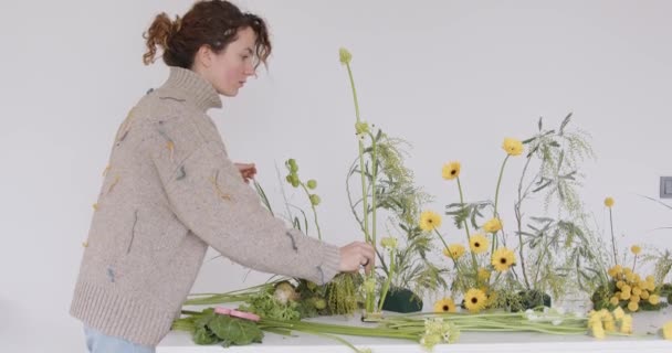 新しい花束を作る女性 花屋は花のオアシスになります 花屋のスタジオで働いている女の子 女性花屋のアーティストは 美しい花束 職場の景色のための花をきれいにします 高品質4K映像 — ストック動画