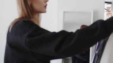 Ayna yansıması genç bir kadın iş günü veya randevu için kıyafet seçiyor, sabahları motive oluyor, soyunma odasında dikiliyor. Giyinmeye çalışan, hafta sonu aktivitesi planlayan mutlu bir milenyum kadını. Yüksek