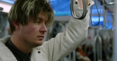 Genç bir adam metro vagonuna biniyor. Üzgün ve yorgun bir adam işten eve metroyla dönüyor. Üzgün bir hippi metroya biner ve tırabzana tutunur. Yüksek kalite 4k görüntü