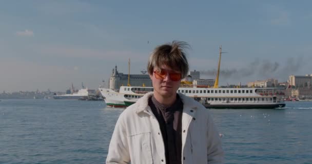 Młody Człowiek Okularach Stoi Nabrzeżu Portu Morskiego Nim Płynie Statek — Wideo stockowe