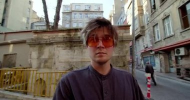 Şehir merkezindeki caddede yürüyen turist önü. Etrafa bir bakın. Gezgin erkek gezginler şehir binalarına bakıyor.