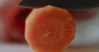 Aşçı havuçları bıçakla doğruyor. Makro gıda araştırması. Havuçlar büyük daireler halinde kesilir. Yüksek kalite 4k görüntü