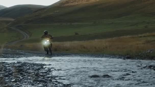 オートバイの旅行者は山の川を渡る フルスピードでオートバイのフォード オートバイの遅い動きの水に水しぶき 自然の中でマウンテンバイクの旅 高品質4K映像 — ストック動画