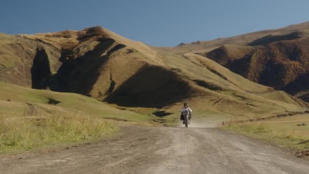 旅行者はマウンテンバイクで山の中の埃っぽい道に乗っています オートバイの運転手が山を駆け抜ける 山の中で極端な冒険 トランプの生活 上の世界中の旅行 — ストック動画