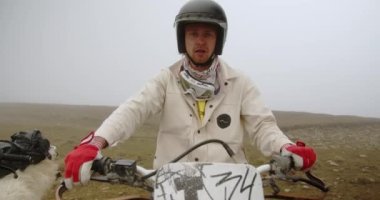 Dağ motosikletçisi, dağ bisikletinin direksiyonunda doğanın arka planına karşı. Direksiyonda yorgun bir motosikletçi var. Yüksek kalite 4k görüntü