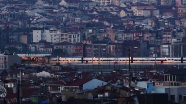 Büyük bir güney şehrinin doğu çeyreğinde. Şehirde şafak ya da alacakaranlık. Vatandaşlar işe metroyla gider. Uzaktan ateş ediyorlar. 300mm. Yüksek kalite 4k görüntü