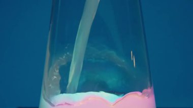 Barbekü kokteyli. Barbekü çekirdeği. Profesyonel barmen mavi bir kokteyli buzla süslüyor. Barmen, çözülmüş arka plan üzerine kokteyller hazırlıyor ve bir kokteyl veriyor. Barmen renkli hazırlanıyor.